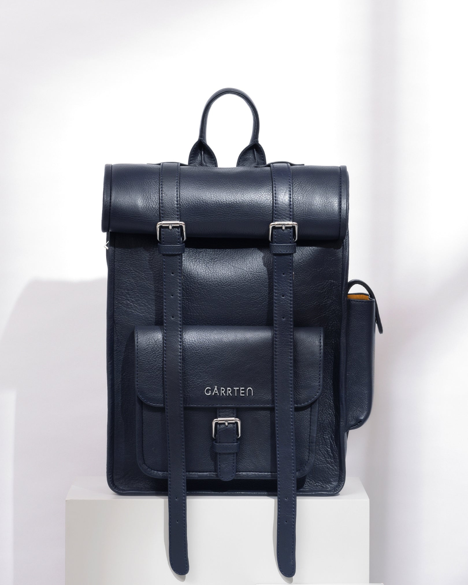midnight blue rolltop leather backpack with 'Garrten' branding on a white background