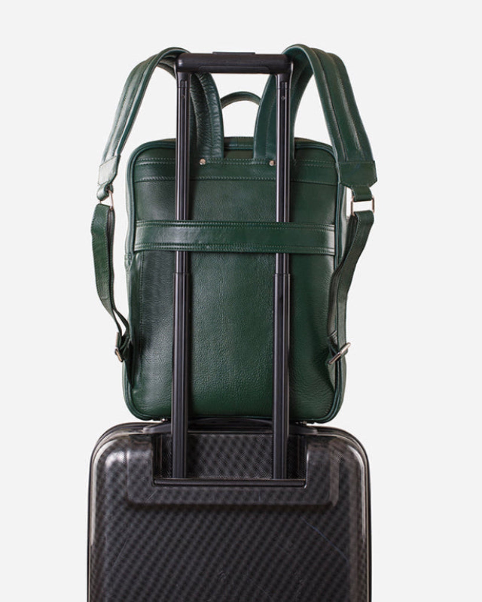 GARRTEN 731 slim full-grain leather backpack — trolley sleeve pass-through in use on wheeled luggage, airline carry-on compatible, white background