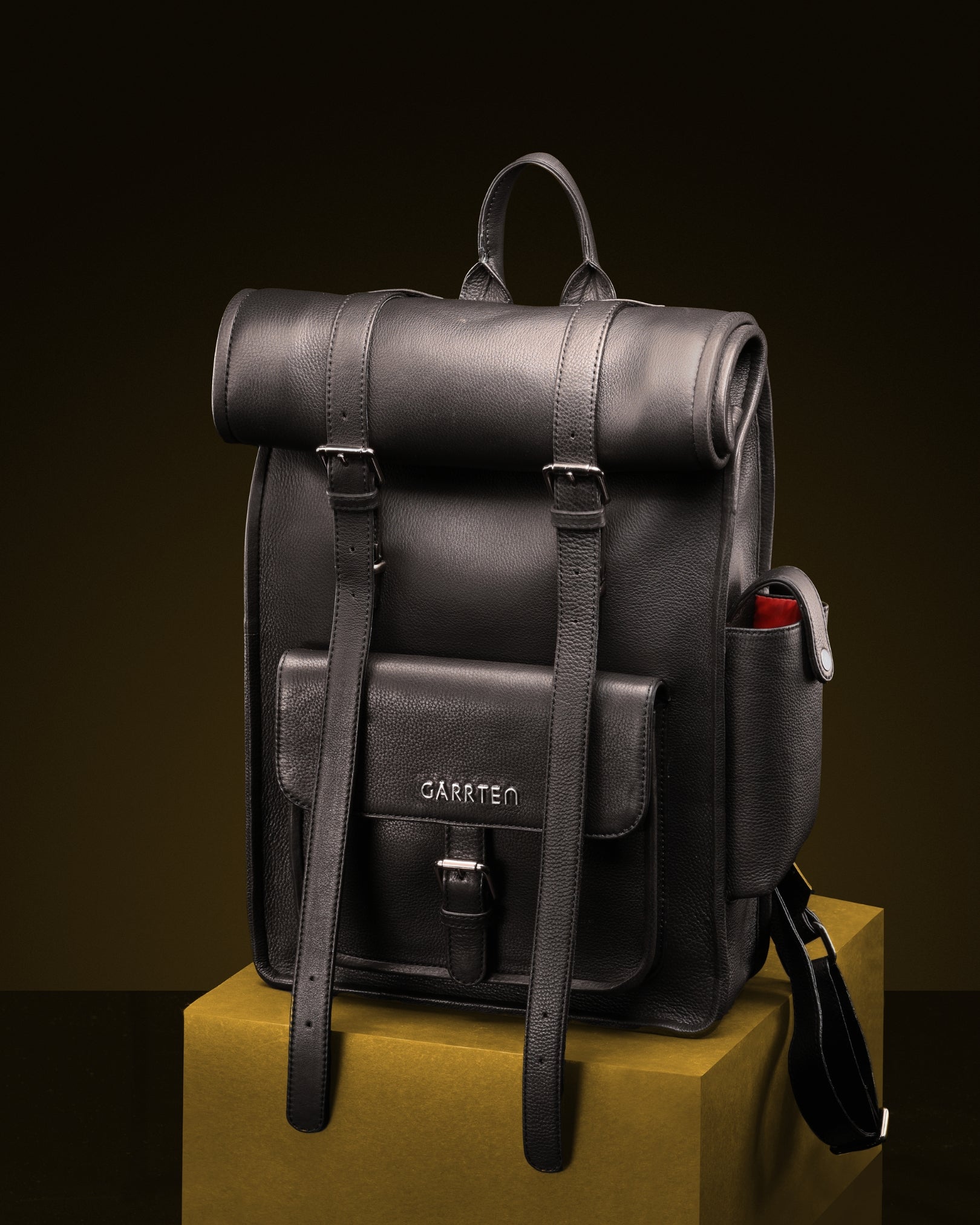 garrten Black rolltop leather backpack on a yellow block with a dark background