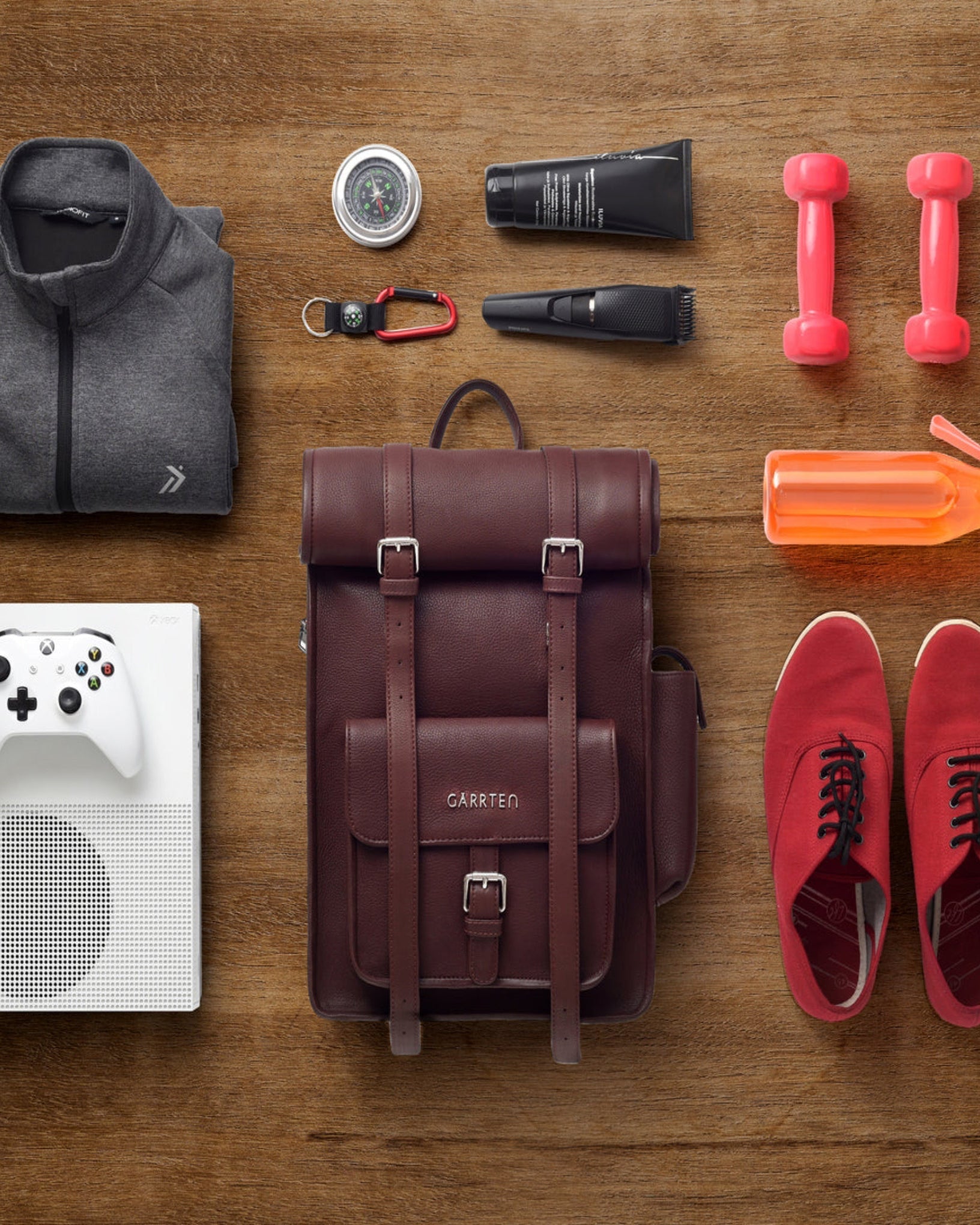 GARRTEN 751 rolltop full-grain leather backpack in vintage mahogany brown — capacity demonstration showing laptop, tablet, phone and essentials laid out beside open bag, white background