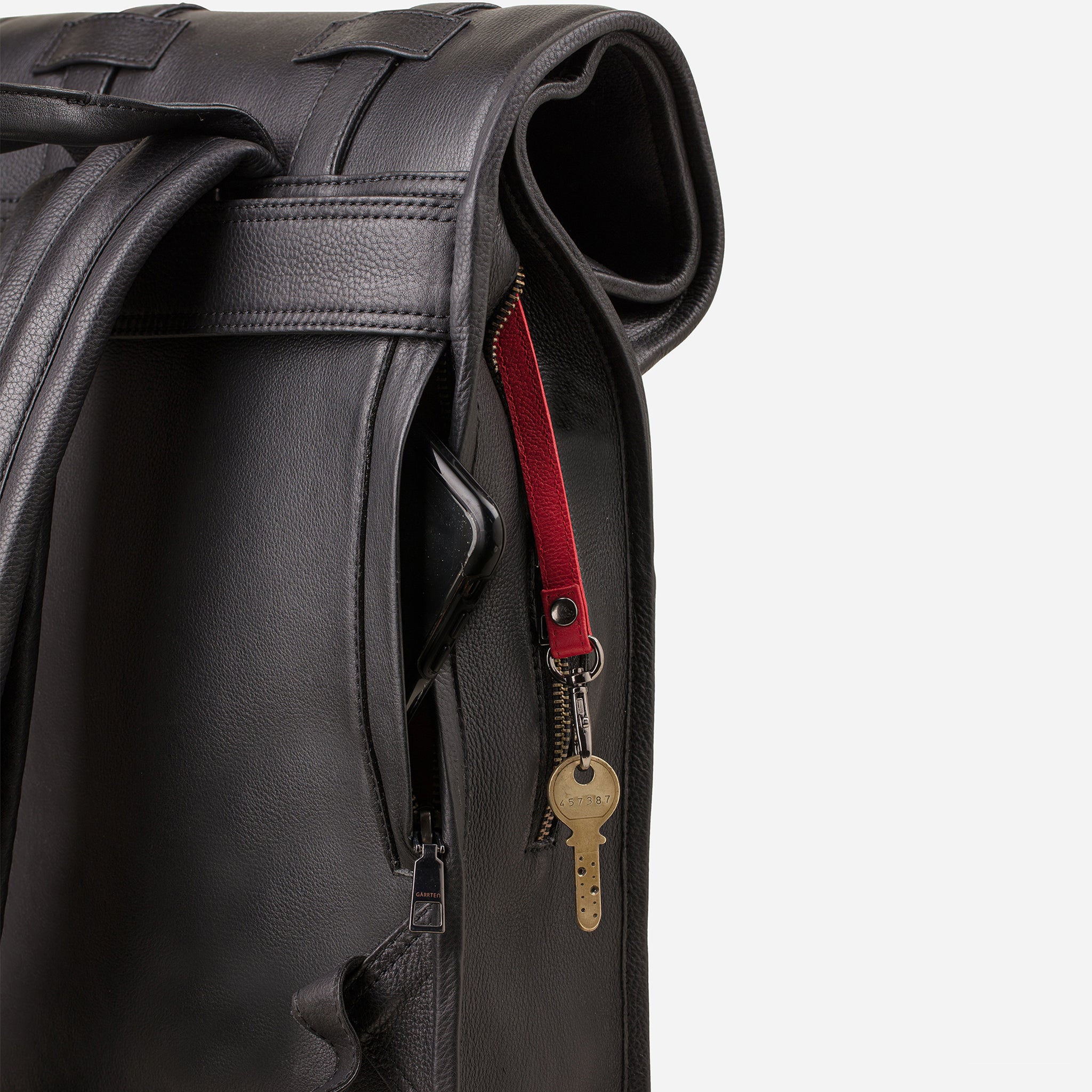 Carbon Black: back view showing quick access pocket and keychain strap of Garrten's rolltop style full grain leather backpack