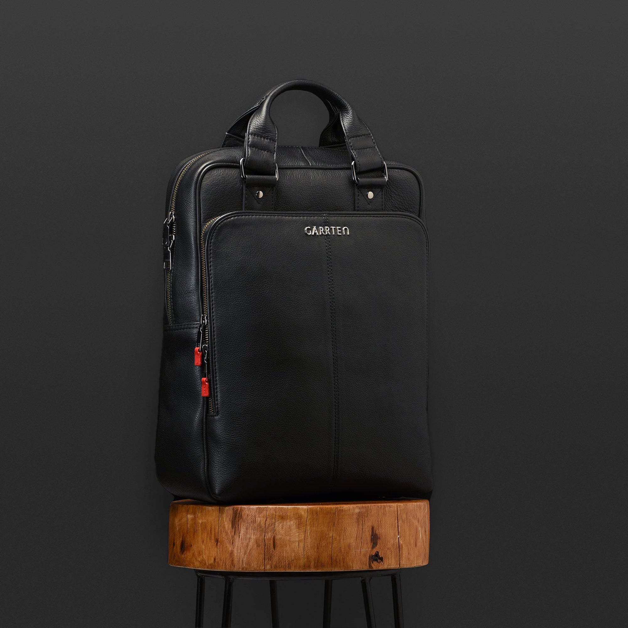Carbon Black: tilt view of Garrten signature convertible full grain leather backpack-moodshot