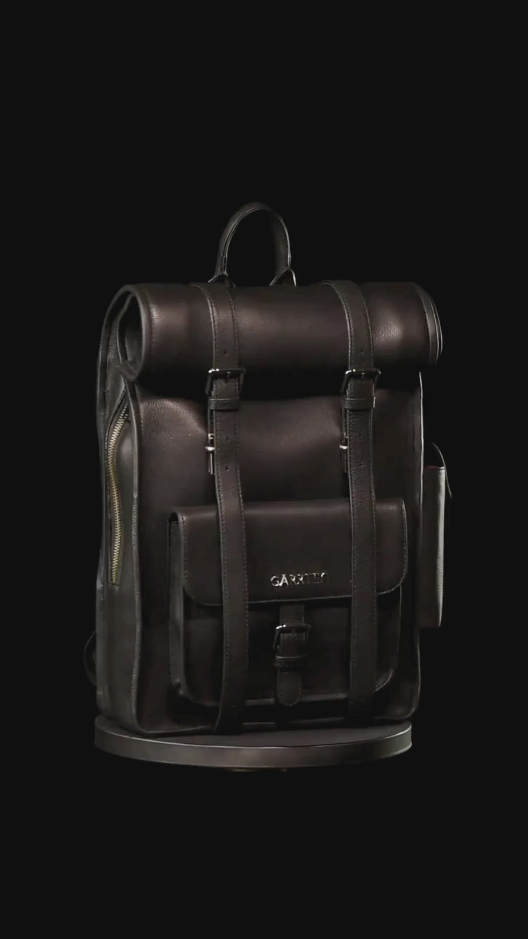 GARRTEN 751 iconic rolltop  leather backpack in carbon black on a turn table— product video in vertical format showing bag 360 degree on a black background