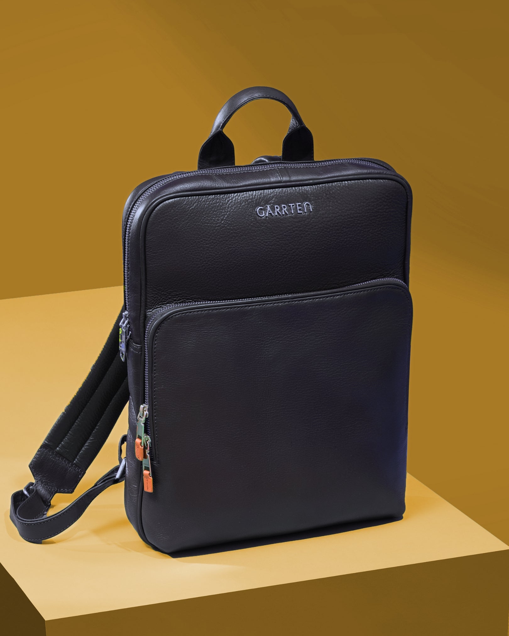 Midnight blue slim backpack with a visible garrten brand  logo on a yellow background