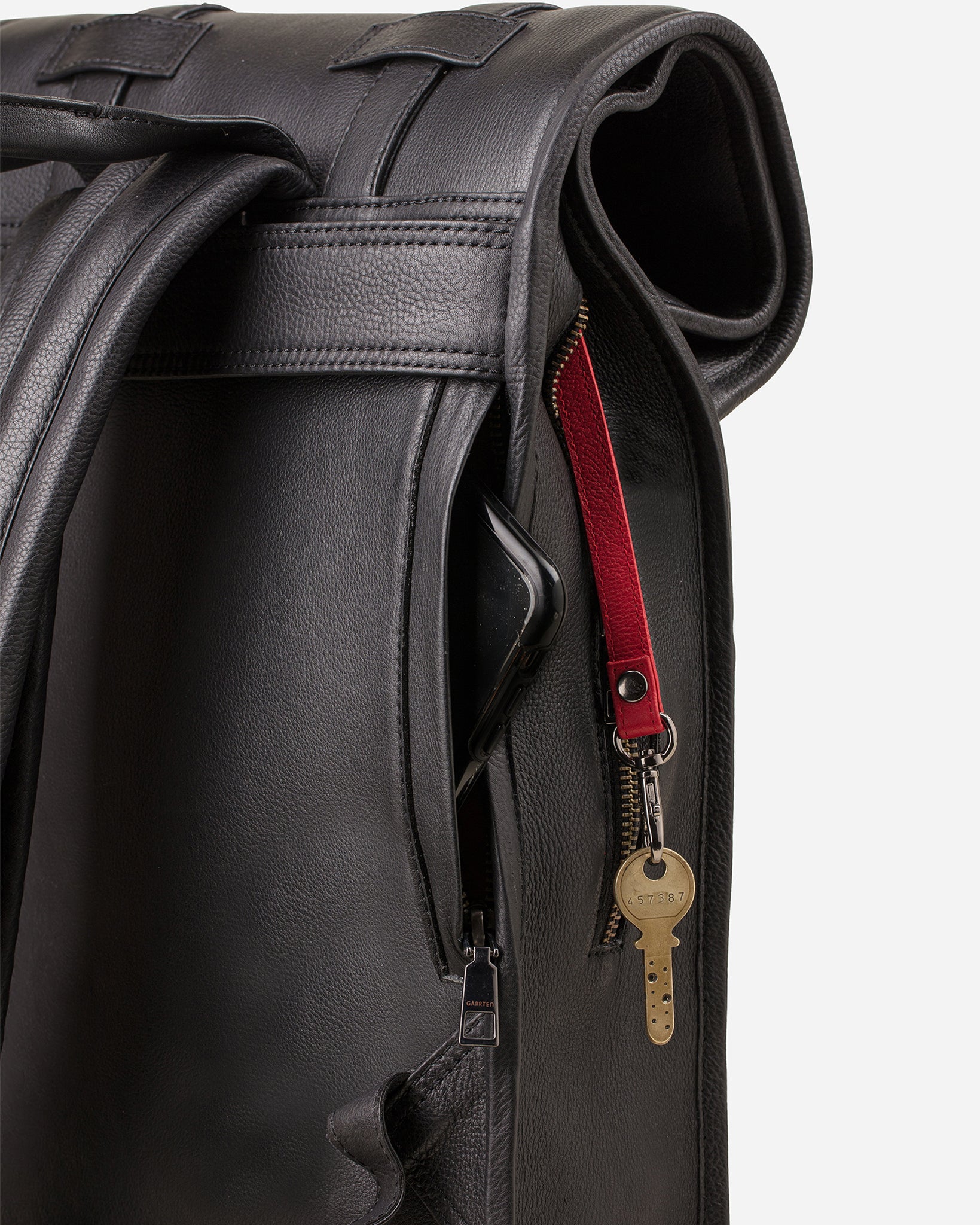 Carbon Black: back view showing quick access pocket and keychain strap of Garrten's rolltop style full grain leather backpack