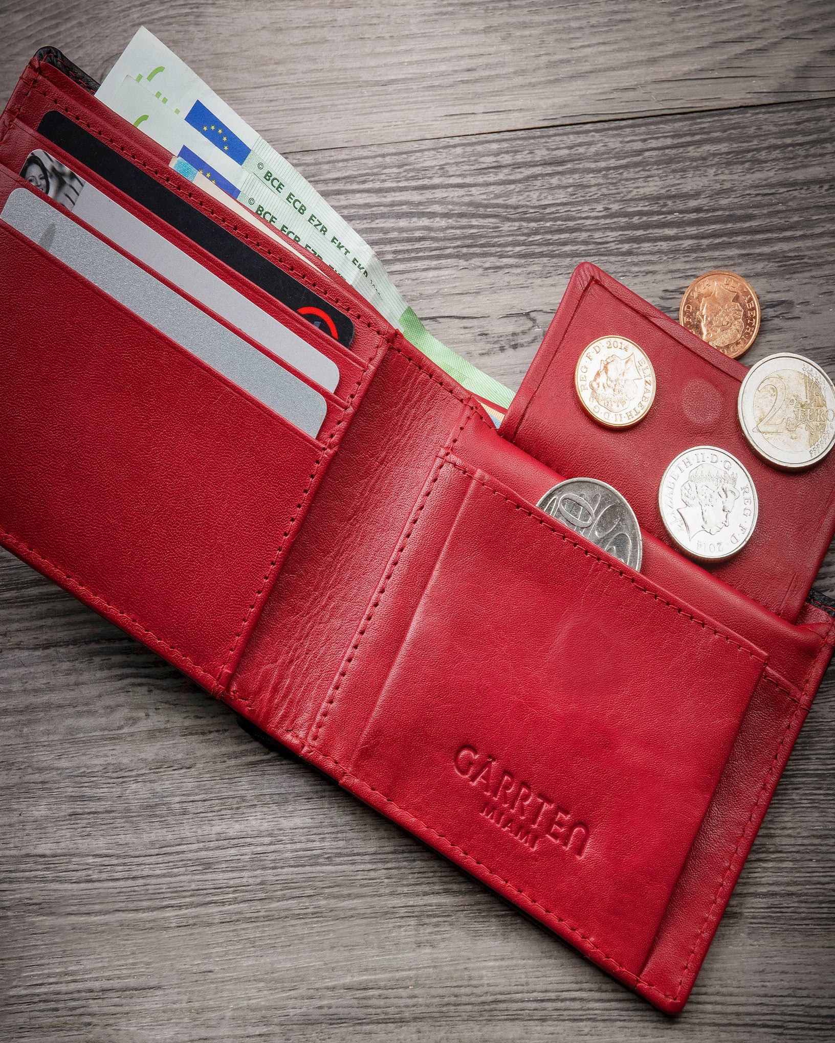 GARRTEN 219 black full grain leather wallet open on wooden surface — card slots, snap-flap coin pocket and red interior lining visible