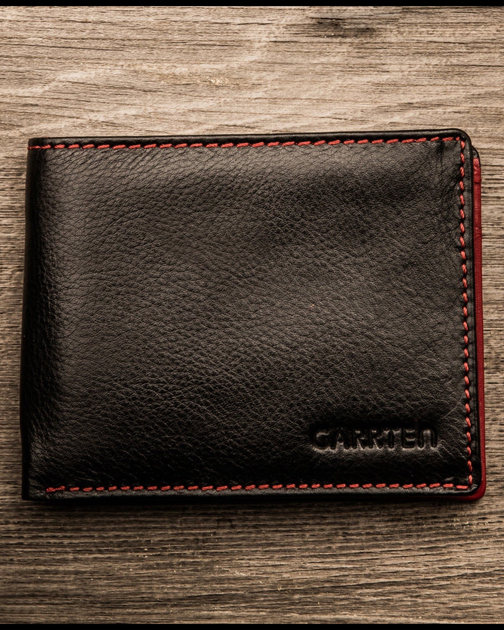 GARRTEN 219 full grain leather wallet — black with red contrast stitching lifestyle mood shot on wooden surface